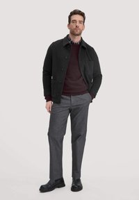 Wollmischung Jacke in Dunkelgrau mit Knopfleiste und Brusttasche, über einem burgunderfarbenen Pullover getragen, kombiniert mit grauen Hosen und schwarzen Stiefeln.