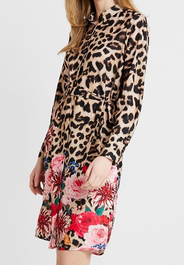 Robe chemise à manches longues imprimée léopard, tissu cintré à la taille, avec un bas floral composé de roses roses et rouges avec des accents bleus.