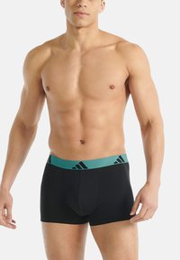 Černé boxerky s elastickým pasem v tyrkysové barvě, zdobené diagonálním vzorem tří pruhů. Vyrobené z elastické látky pro pohodlí.