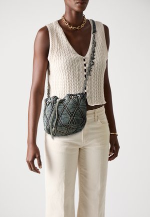 Denim bucket bag with a quilted pattern, dark blue color, and drawstring closure, featuring a metallic chain shoulder strap.