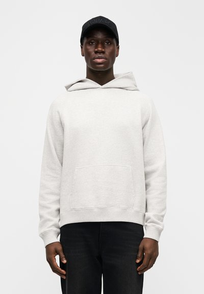 Světlě šedá mikina s kapucí, klokankovou kapsou, stahovací šňůrkou a pružnými manžetami. Kombinována s tmavými džínami a černou čepicí s nápisem "VOLTAIRE".