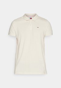 Cremfarbener kurzärmeliger Poloshirt mit einer Zwei-Knopf-Leiste und kleinem rot-weiß-blauen rechteckigen Logo auf der linken Brust.
