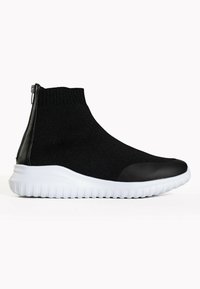 Schwarze Textilstiefeletten mit einem gerippten Strickobermaterial, weißer Gummisohle und schwarzem Zehenkappen. Verfügt über einen seitlichen Reißverschluss für ein einfaches An- und Ausziehen.