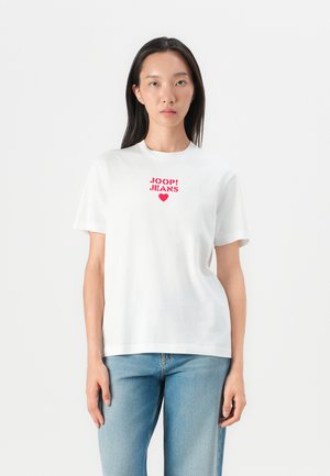 Weißes Baumwoll-T-Shirt mit rotem "JOOP! JEANS"-Grafik- und Herzdesign auf der Brust, kombiniert mit hellblauen Denim-Jeans.