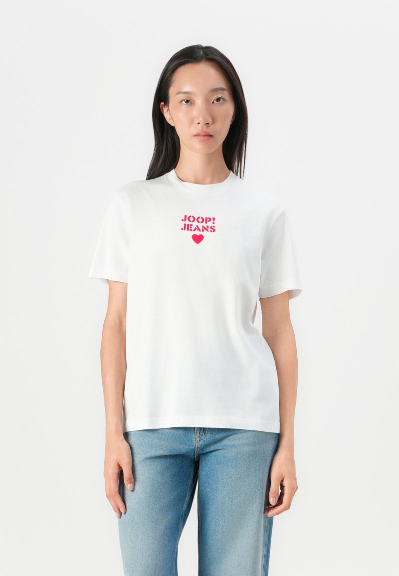 White cotton t-shirt featuring red "JOOP! JEANS" graphic and heart design on the chest, paired with light blue denim jeans.