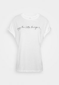 Vit kortärmad t-shirt i mjuk bomull med avslappnad passform, med kursiv svart text "njut av de små sakerna" på framsidan.