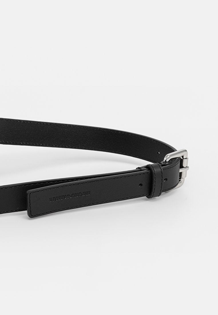 Cintura in pelle nera con una texture liscia, fibbia in metallo argento e un bordo cucito in modo ordinato, con un'etichetta del marchio sulla cinghia.