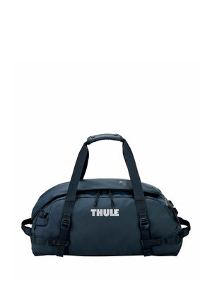 Sac de voyage Thule noir avec doubles poignées, fermeture éclair supérieure et sangles latérales ajustables sur fond blanc.