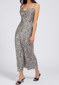 Sukienka maxi w panterkę z cienkimi regulowanymi ramiączkami, dekoltem w kształcie czołgu i gładkim materiałem sięgającym do kostek. Czarne sandały na obcasie.