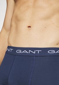 Jūras zilas kokvilnas bokseru šortus ar baltu GANT logo uz elastīgā josta, ar gludu tekstūru un pieguļošu dizainu.
