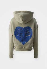 Felpa color verde oliva con un grande design a forma di cuore blu, realizzato con linee rigate, sulla parte posteriore; presenta un cappuccio e polsini elasticizzati.