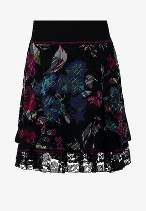Mujer con una blusa de manga corta color malva, falda negra con estampado floral y encaje, medias negras transparentes, bailarinas negras y un pequeño bolso negro.