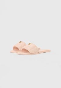 Pink quilted slide sandals with an open toe, flat sole, and gold detailing. Soft material with a smooth texture.