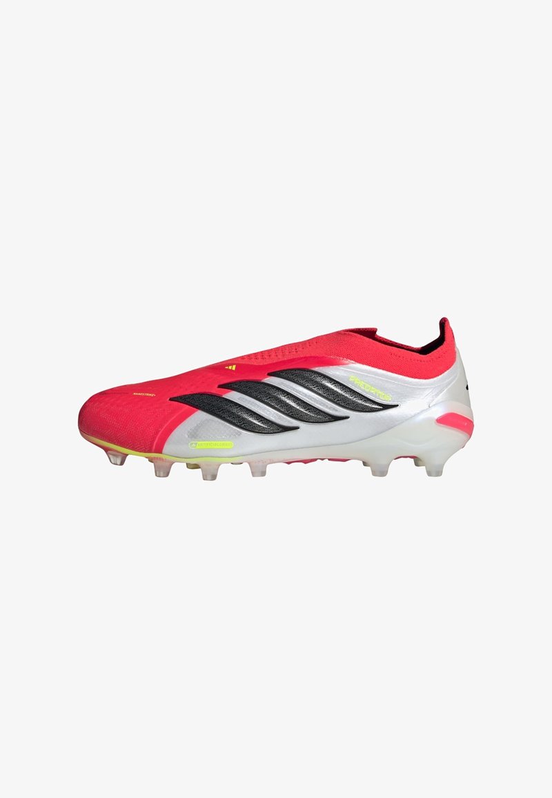 Κόκκινο και άσπρο παπούτσι ποδοσφαίρου Adidas Predator με μαύρες ρίγες, νέον κίτρινες λεπτομέρειες και καρφιά για τεχνητά χλοοτάπητα.