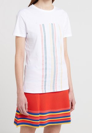 White t-shirt featuring vertical lines in blue, pink, and yellow. Paired with a red skirt with vertical stripes in blue, yellow, and red.