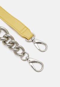 Żółty skórzany pasek mocujący do srebrnego łańcucha metalowego o teksturowanym wykończeniu; wyposażony w dwa srebrne metalowe karabińczyki.