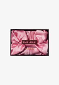 Ren silketurban i myk rosa, med en jevn tekstur og en stor sløyfe. Boksinnpakningen har merkevare i kontrasterende farger.