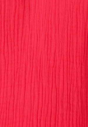 Tissu rouge vif avec une texture douce et froissée et de fines rides verticales sur toute la surface.