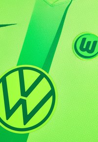Helle grüne Sporttrikot mit strukturiertem Stoff, V-Ausschnitt-Design und einem großen, kreisförmigen Logo in passendem Grün mit dunklen Akzenten.