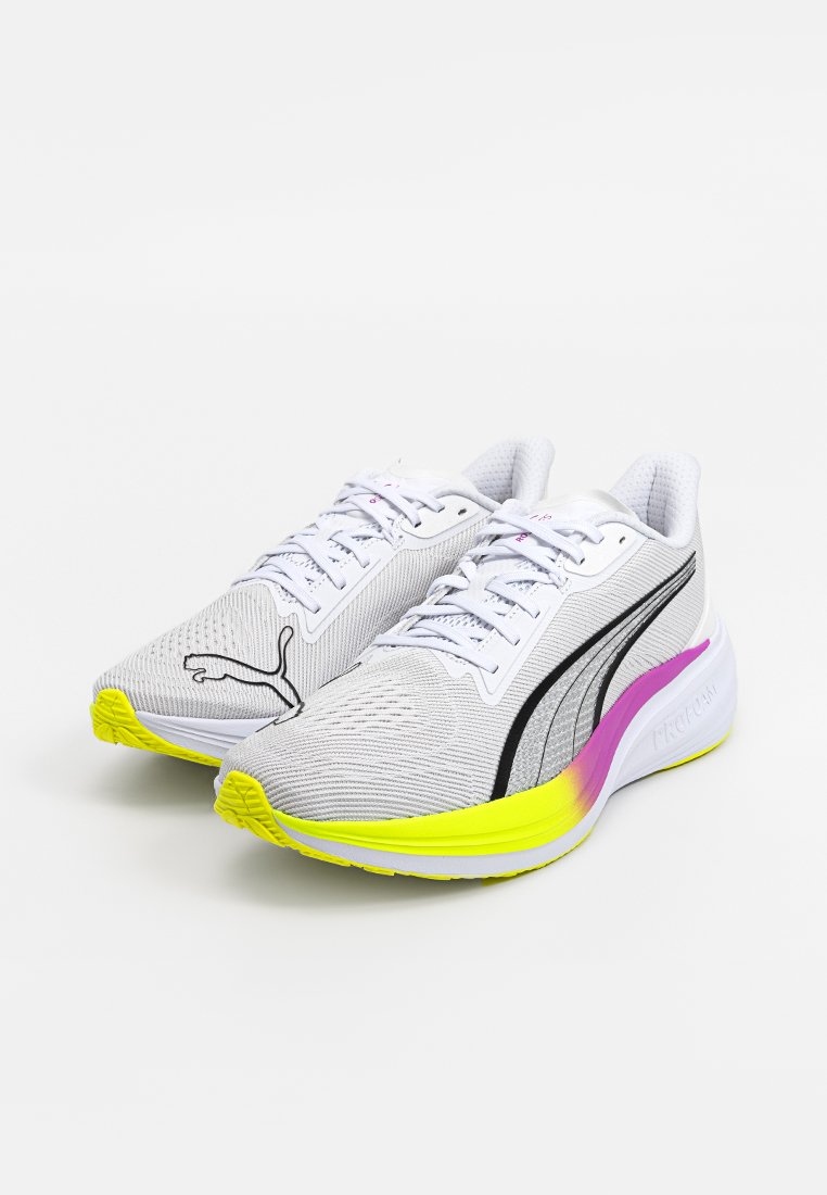 Zapatillas deportivas blancas con una parte superior de malla texturizada, rayas negras y acentos en amarillo neón y rosa en la suela. Presentan cordones y detalle del logotipo.