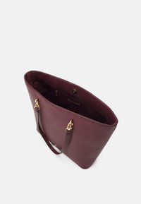 Burgundy läder tote-väska med gyllene detaljer, slät textur, en axelrem och en öppen topp som visar en rymlig insida med en dragkedjeficka.