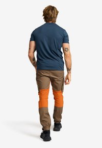 Blå kortärmad t-shirt i kombination med bruna cargo-byxor med ljusa orange kn�älappar. Svarta skor fulländar outfiten.