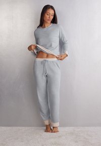 Grå, mjuk bomullsloungewear-set med långa ärmar och joggerbyxor med beige muddar och dragsko i midjan. Ingen mönstring eller hårdvara.