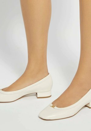 Chaussures à talon bloc en cuir blanc avec un bout carré, ornées d'un petit accent doré à l'avant et d'une texture lisse. Talon bas et structuré.