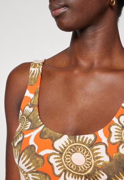 Top de tirantes multicolor con un estampado floral en naranja, verde y blanco, con un escote amplio en forma de barco y tejido texturizado.