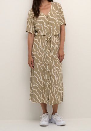 Robe midi beige avec un col en V, des manches courtes et des rayures blanches ondulées. Présente des boutons à l'avant et une ceinture nouée à la taille.