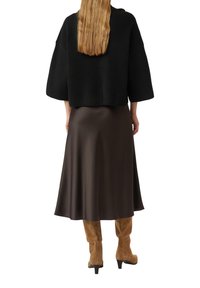 Black knit cropped sweater, brown satin midi skirt, and tan suede knee-high boots. Textured fabric contrasts with smooth skirt.
