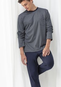 Maglietta a righe blu navy a maniche lunghe con scollatura rotonda e taschino sul petto, abbinata a pantaloni blu navy uniti. Tessuto morbido con vestibilità comoda.