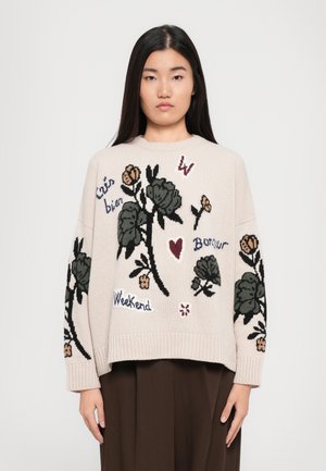 Pull en tricot crème avec broderies florales en vert, rose et bordeaux. Présente des phrases telles que "Weekend" et "Bonjour", avec des poignets et un ourlet côtelés.