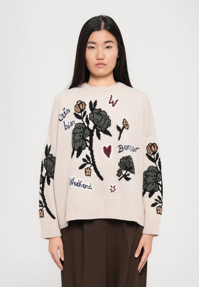 Pull en tricot crème avec broderies florales en vert, rose et bordeaux. Présente des phrases telles que "Weekend" et "Bonjour", avec des poignets et un ourlet côtelés.