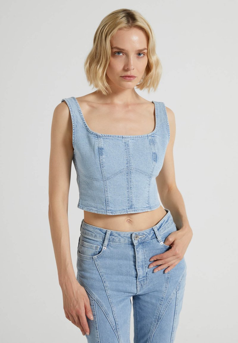 Top in denim azzurro chiaro, cropped, con scollatura quadrata e spalline spesse, caratterizzato da cuciture strutturate e un design aderente.