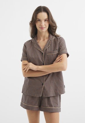 Bruin en beige geblokt pyjama set met korte mouwen en shorts. Kenmerkt zich door contrasterende piping langs de randen en een klein borstzakje.