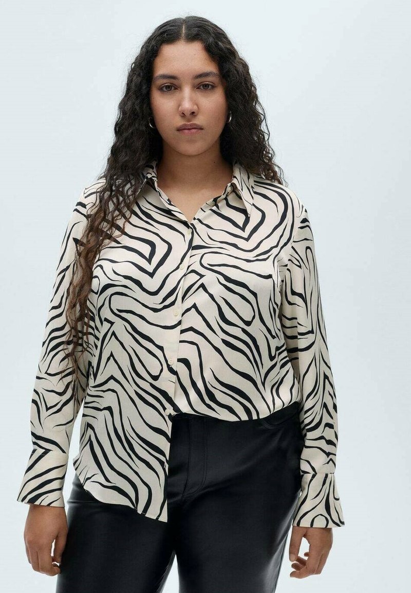 Camicia a maniche lunghe color crema con un motivo a strisce zebra nere. Presenta una chiusura con bottoni e un colletto classico, realizzata in tessuto morbido.