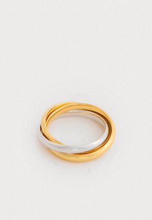 Anel triplo com bandas entrelaçadas em ouro e prata, com um acabamento liso e polido, exibindo um design circular.
