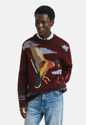Maroon knitted sweater featuring a bird motif in colors including green, yellow, and blue. Ribbed collar and hem, with blue and red accents.