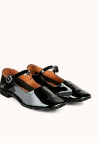 Ballerines en cuir verni noir avec un nez pointu, une bride de cheville avec boucle ronde et un petit talon. L'intérieur est doublé en tan.