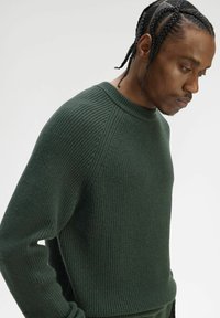 Maglione verde scuro a coste in maglia con scollo tondo e maniche raglan, caratterizzato da un motivo testurizzato e una vestibilità comoda.