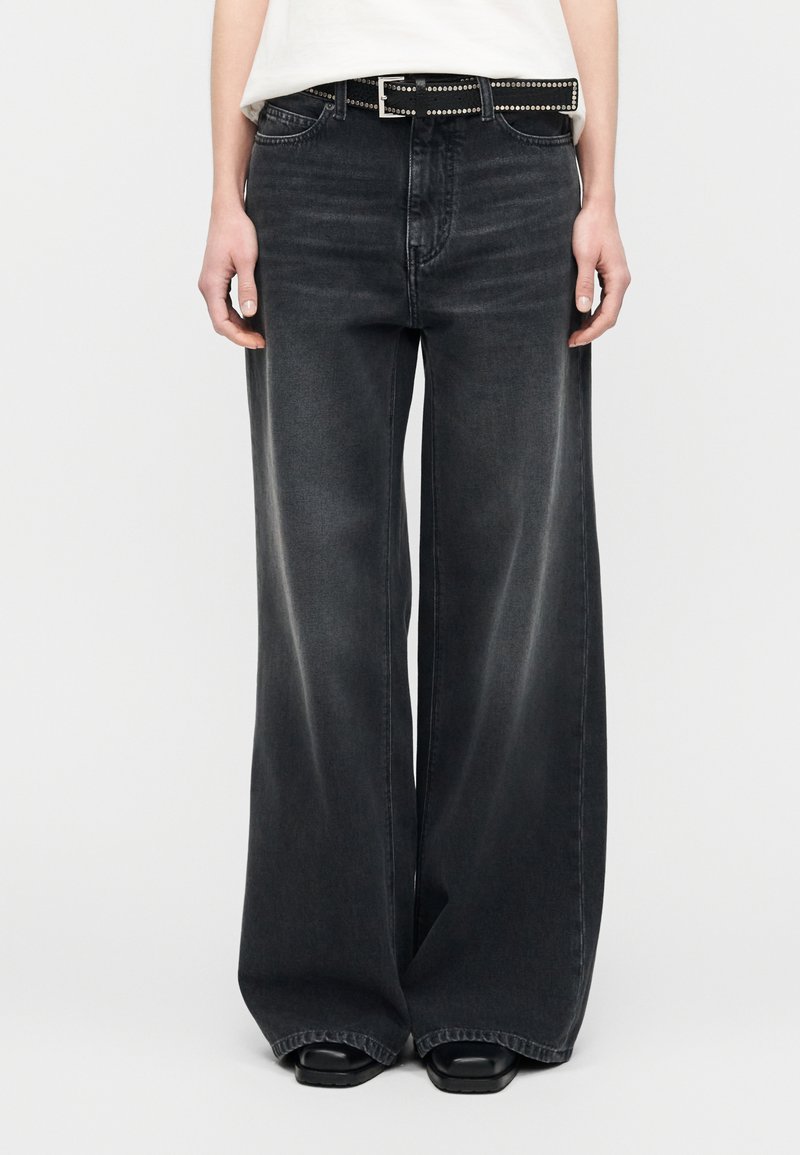 Μαύροι τζιν με φαρδιά μπατζάκια σε ξεβαμμένο ντέ νιμ, με ψηλή μέση, σχεδιασμό με πέντε τσέπες και μαύρη ζώνη με τρουκ για διακοσμητική λεπτομέρεια.