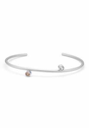 Åben sølvcuff-armbånd med to små runde sten i bezel-sætning, en klar og en lys brun, i hver ende.