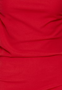 Tela roja con pliegues y arrugas visibles, mostrando textura y suavidad.