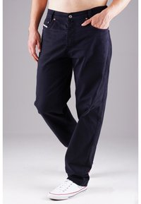 Navy blue cotton pants with a relaxed fit, featuring front pockets and subtle stitching details. Worn with white sneakers for contrast.