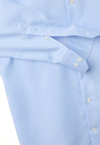 Camicia azzurro chiaro con sottili strisce verticali bianche, polsini con bottoni e bottoni bianchi sulle maniche e davanti.