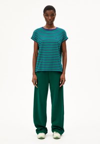 Striped green and blue t-shirt with rolled sleeves, paired with loose green pants and light green sneakers. Smooth cotton texture.