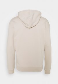 Sudadera beige con una textura suave, capucha con cordones y puños y dobladillo acanalados. La vista trasera muestra un corte relajado y un diseño minimalista.
