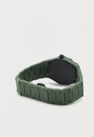 Πράσινο λουράκι ρολογιού με συνδέσμους, με μαύρη πίσω θήκη ρολογιού και κορόνα ρύθμισης σε λευκό φόντο.