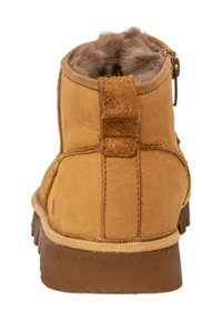 Tan ruskindsankelstøvler med blødt pelsfore, der har en bageste løkke og en struktureret gummisål. Lynlåsdetalje på siden.